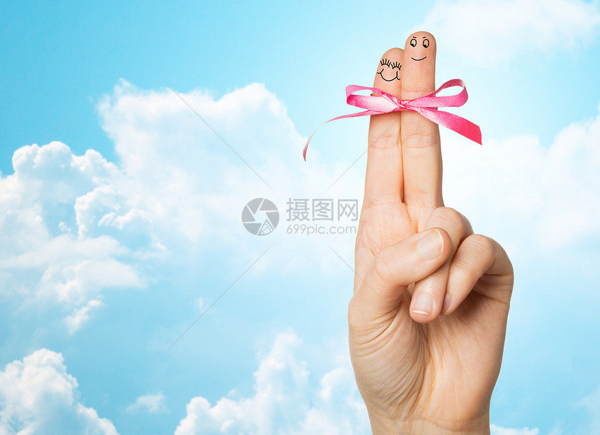 手势,爱,假期身体部位的用两根手指绑蓝色的天空云彩背景上的粉红结上图片