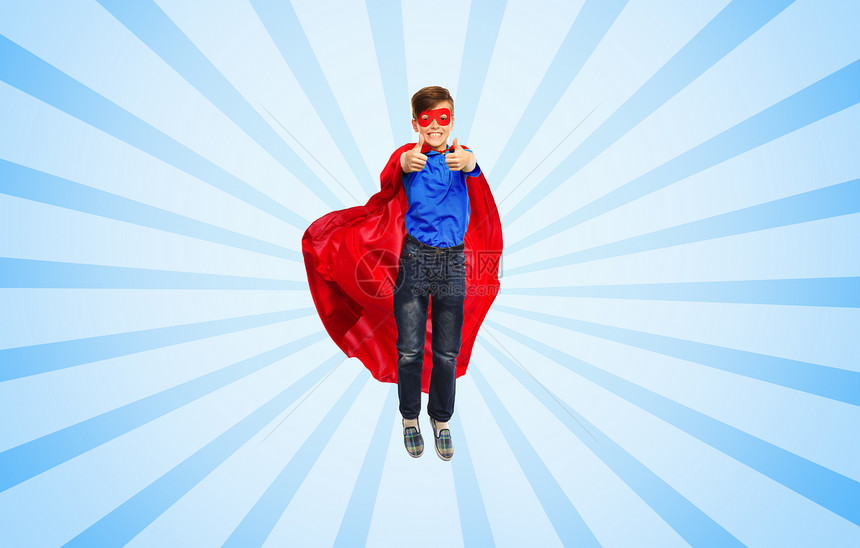 幸福,自由,童,运动人的男孩穿着红色超级英雄斗篷具空中飞行,并蓝色爆发射线背景上竖大拇指图片