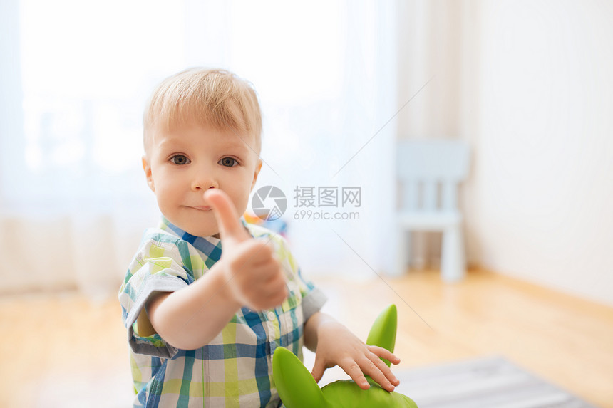 童,玩具人的快乐的小男孩玩骑玩具马,并家里竖大拇指图片