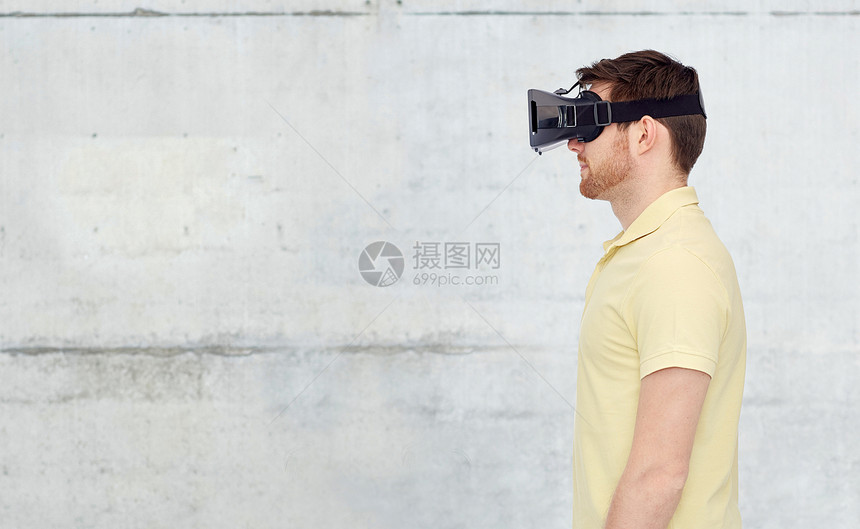 三维技术,虚拟现实,娱乐活动人的轻人与虚拟现实耳机三维眼镜混凝土灰墙背景图片