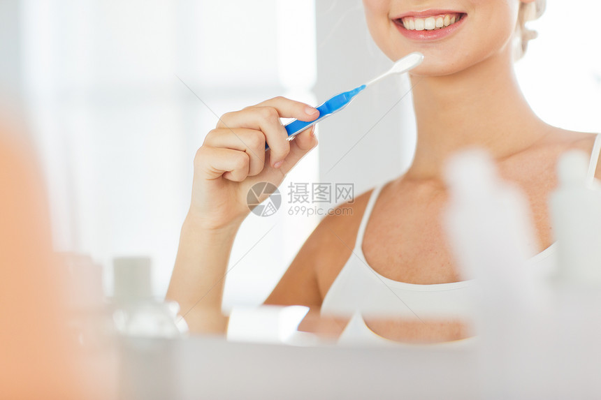 保健,牙科卫生,人与美的微笑的轻妇女牙刷清洁牙齿镜子家里的浴室图片
