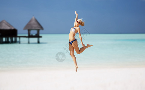 人,旅游,暑假假期的快乐的轻女人跳过异国情调的马尔代夫海滩与平房背景图片