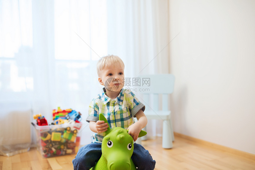 童,玩具人的快乐的小男孩家里玩骑玩具马图片