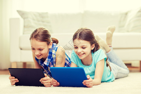 人,孩子,技术,朋友友谊的快乐的小女孩与平板电脑躺家里的地板上图片
