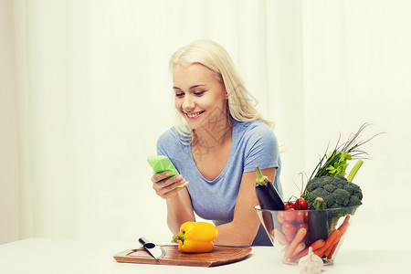 健康饮食,素食,饮食人的微笑的轻妇女与智能手机烹饪蔬菜家图片