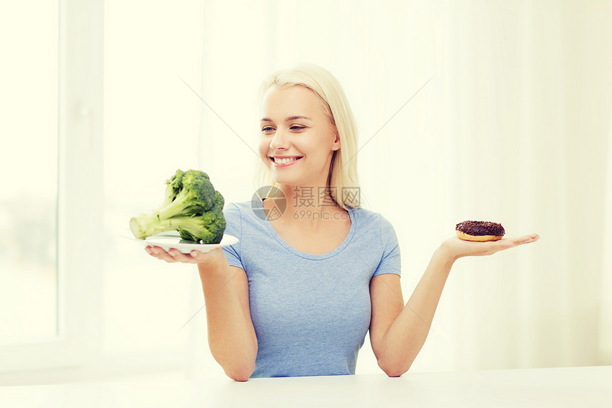 健康饮食,垃圾食品,饮食选择的人的微笑的女人选择西兰花甜甜圈家里图片