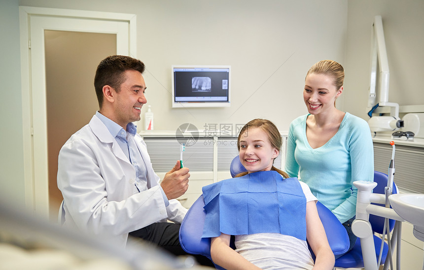 人,医学,口腔科保健快乐的男牙医向病人女孩她的母亲牙科诊所办公室展示牙刷图片