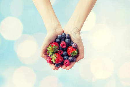 健康的饮食,节食,素食人们的靠近女人的手,着同成熟的夏季浆果蓝光背景下图片
