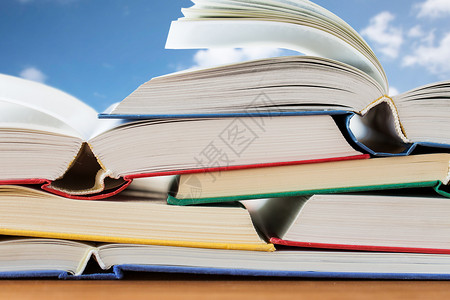 教育学校文学阅读知识蓝天云层背景下,把书放木桌上图片