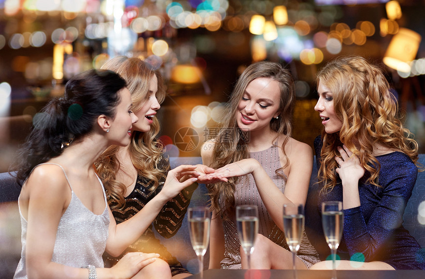 庆祝,朋友,单身派假期快乐的女人夜总会用香槟杯向她的朋友展示订婚戒指图片