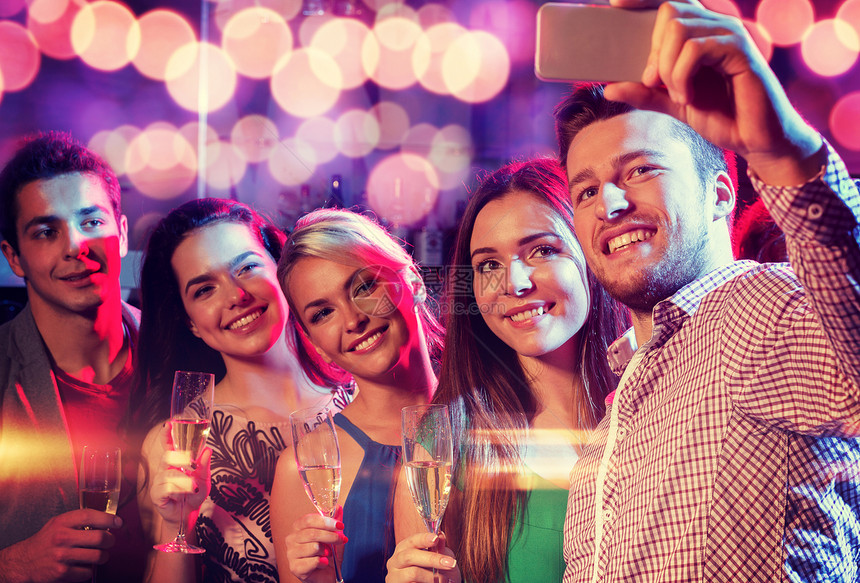 派,假期,技术,夜生活人们的微笑的朋友带着杯香槟智能手机俱乐部自拍图片