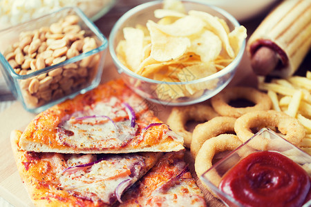 快餐健康的饮食比萨饼,油炸鱿鱼戒指,薯片,花生番茄酱木制桌视图图片