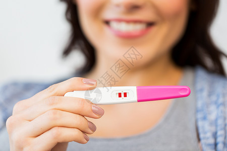 怀孕,生育,生育人的接近快乐的女人与积极的家庭怀孕测试图片