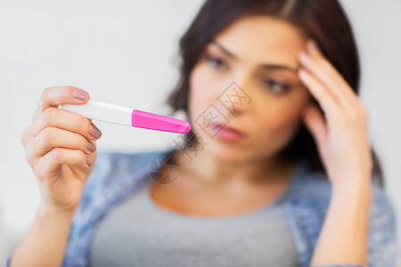 怀孕,生育,生育人的接近悲伤快乐的女人看家里的怀孕测试图片