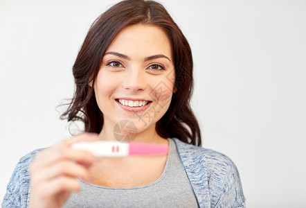 怀孕,生育,生育人的快乐微笑的女人持阳的家庭怀孕测试背景图片