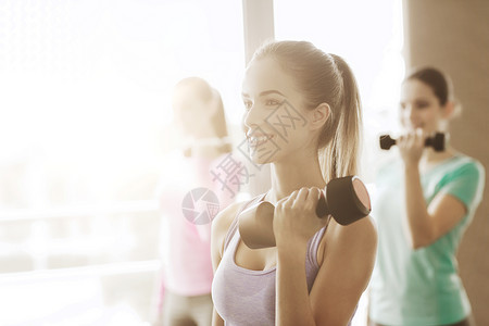 健身,运动,训练生活方式的快乐的妇女与哑铃弯曲肌肉健身房图片