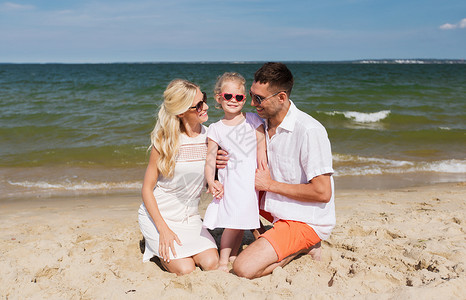 旅行,度假,收养人们的快乐的家庭与戴太阳镜的小女孩夏天的海滩上交谈图片