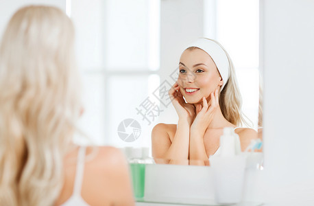 美丽,皮肤护理人的微笑的轻女人发带触摸她的脸镜子家里的浴室背景图片