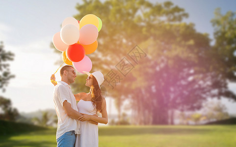 爱情,关系,假期,约会人的微笑的夫妇戴着太阳镜,夏天的公园背景下拥抱气球图片