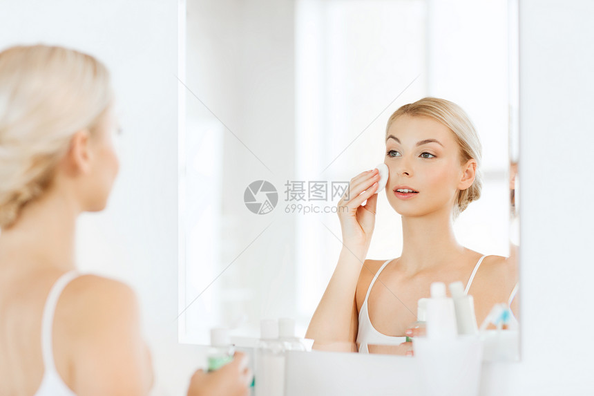 美丽,皮肤护理人的微笑的轻妇女应用乳液棉花盘,以洗她的脸浴室图片