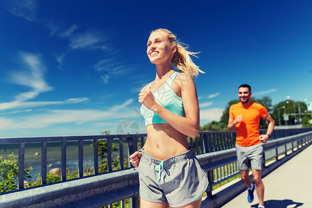 健身,运动,友谊健康的生活方式微笑的夫妇夏季海边跑步图片
