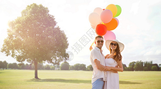 爱情,关系,假期,约会人的微笑的夫妇戴着太阳镜,夏天的公园背景下拥抱气球图片