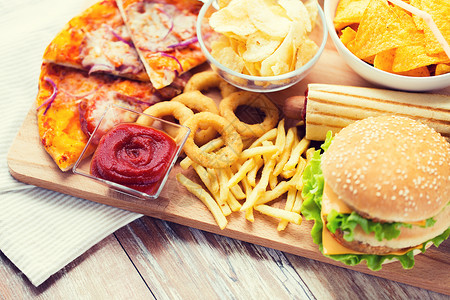 快餐健康的饮食汉堡奶酪汉堡,油炸鱿鱼圈,炸薯条,比萨饼番茄酱木制桌视图图片
