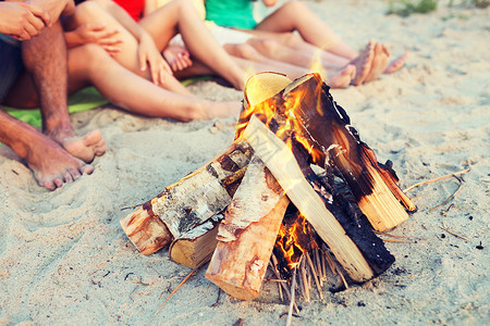友谊,幸福,暑假,假期人们的亲密的朋友坐靠近火的海滩图片
