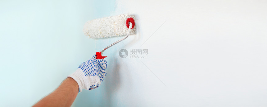 修理,建筑家庭男手套油漆墙与滚筒图片