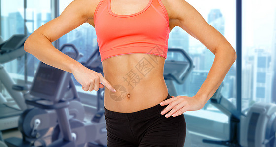 人,健身运动近距离的女教练指着她的腹部健身房的机器背景图片