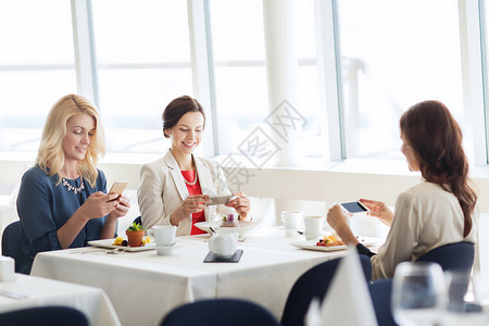 人,技术生活方式的快乐的女人用智能手机餐厅拍照食物图片