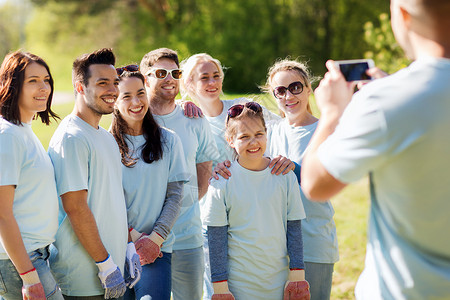 志愿服务慈善人队合作环境群快乐的志愿者公园用智能手机拍照图片