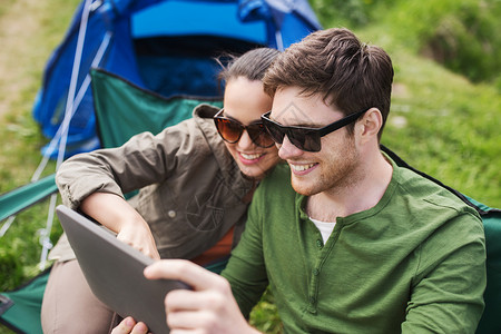 旅行,徒步旅行,技术,旅游人的微笑夫妇与平板电脑坐露营帐篷的椅子上图片