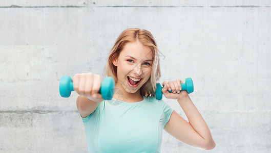 健身,运动,锻炼人的微笑美丽的运动女人与哑铃战斗站灰色的混凝土墙背景图片