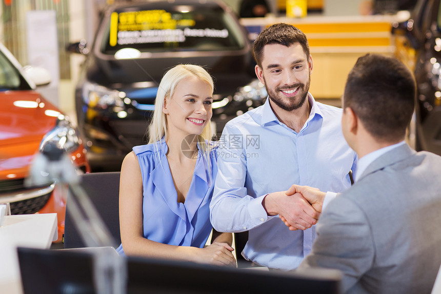 汽车业务,汽车销售,人们的愉快的夫妇与经销商握手车展沙龙图片