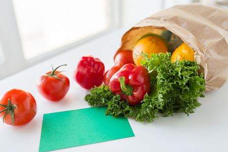 绿色纸袋烹饪,饮食,素食健康饮食纸袋与新鲜成熟多汁的蔬菜蔬菜厨房的桌子上背景