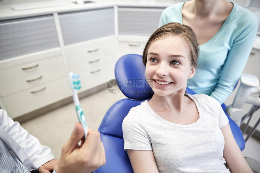 人,医学,口腔科保健快乐的男牙医向病人女孩她的母亲牙科诊所办公室展示牙刷图片