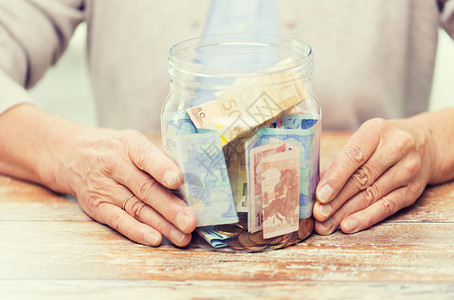 储蓄,金钱,金保险,退休人的亲密的老年女子的手与钱璃罐图片