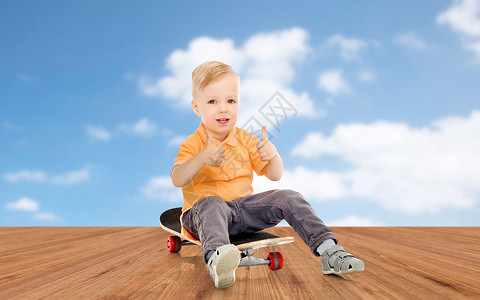 童,运动,休闲,手势人的快乐的小男孩坐滑板上,蓝天木地板背景上竖大拇指图片