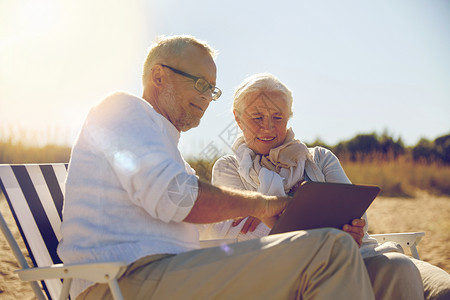 家庭,龄,旅游,旅游人的快乐的老夫妇与平板电脑电脑休息折叠椅夏季海滩图片
