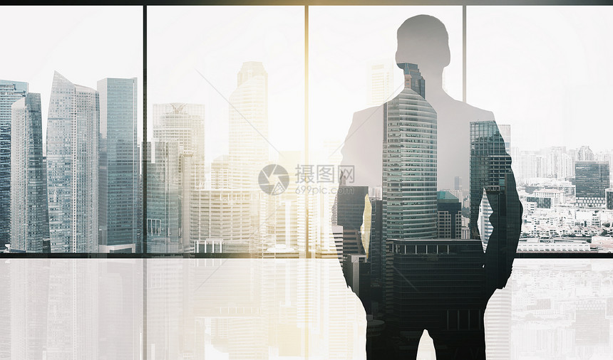 商业人的商人的轮廓办公室窗口新加坡城市摩天大楼的背景阳光双曝光效果办公室背景下商人的剪影图片