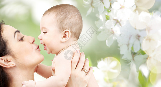 家庭,母亲,养育,人儿童保育的快乐的母亲亲吻可爱的婴儿绿色的自然背景背景图片
