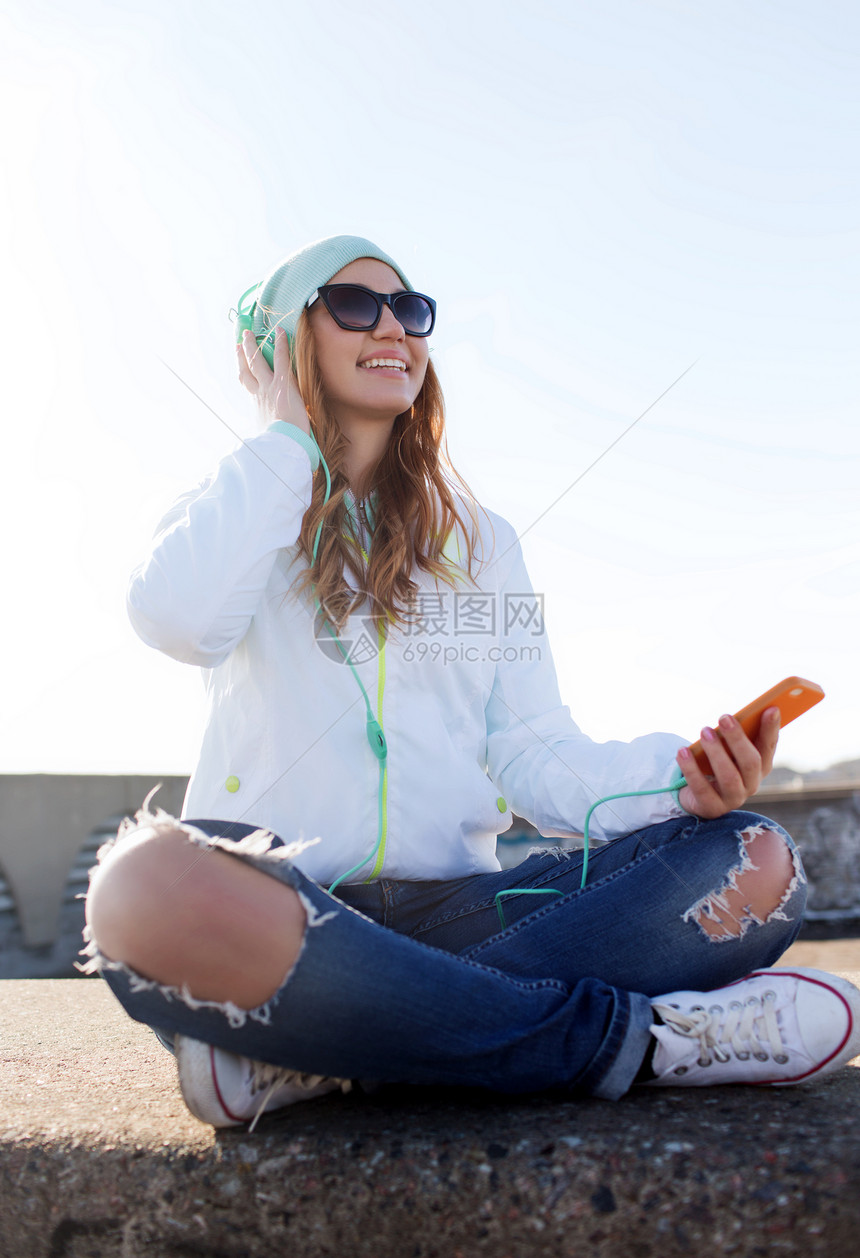 技术生活方式人们的微笑的轻妇女十几岁的女孩,带着智能手机耳机户外听音乐图片