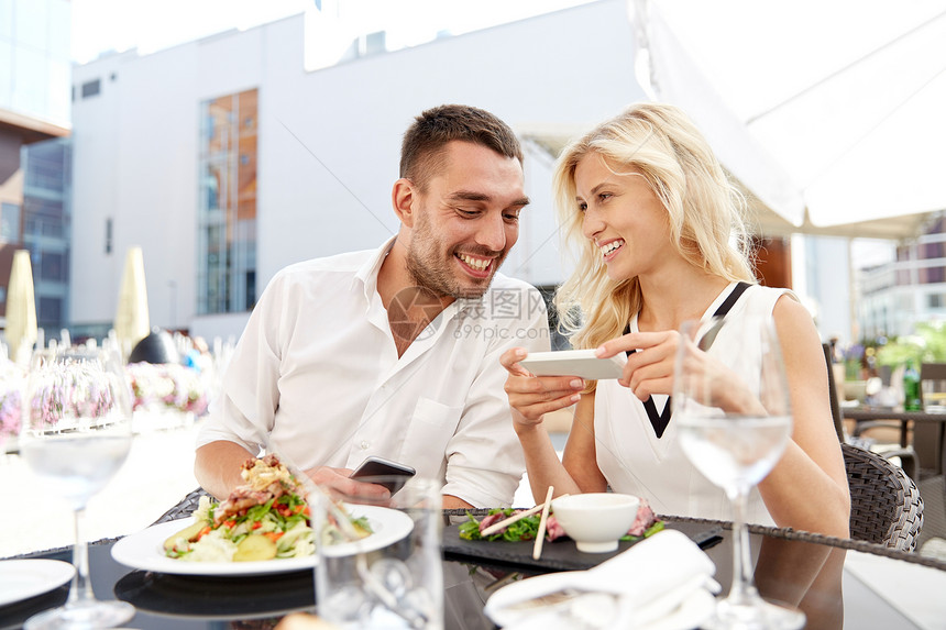 爱情,约会,技术,人关系的微笑的幸福夫妇与SmatPhone餐厅露台图片