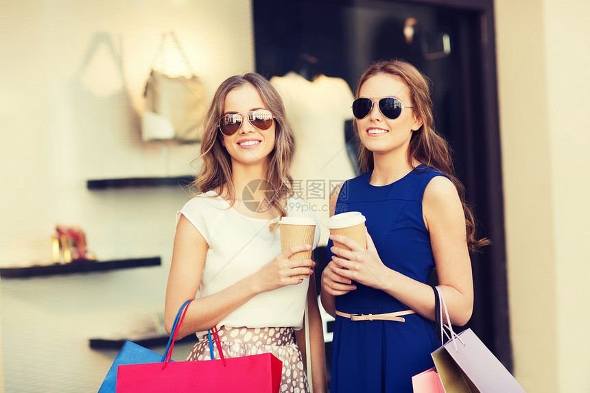 销售,消费主义人们的快乐的轻女城市的商店橱窗里着购物袋咖啡纸杯图片