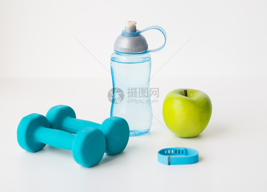 运动,健康的生活方式物品哑铃与健身跟踪器,绿色苹果水瓶白色背景图片