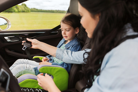 家庭,交通,道路旅行人们的快乐的女人系着孩子的安全安全带车里图片
