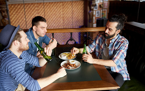 人休闲友谊单身汉聚会的快乐的男朋友酒吧酒吧喝瓶装啤酒吃零食图片