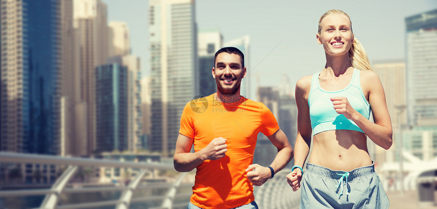 健身,运动,锻炼健康的生活方式微笑夫妇跑步慢跑迪拜城市街道背景图片