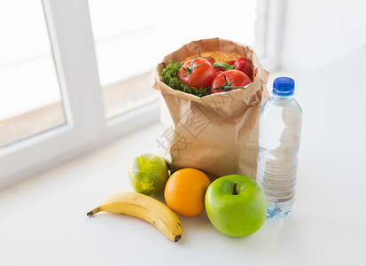 烹饪,饮食,素食健康饮食纸袋与新鲜成熟多汁的水果蔬菜水瓶厨房的桌子上图片